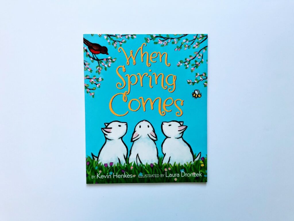 A picture of a book with 3 bunnies on the cover looking at the title.